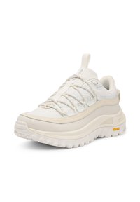 Kevyt, off-white värinen tennari, jossa on teksturoitu päällinen, joustavat nauhat ja paksu kermaisa pohja. Varustettu oranssilla Vibram-logolla.