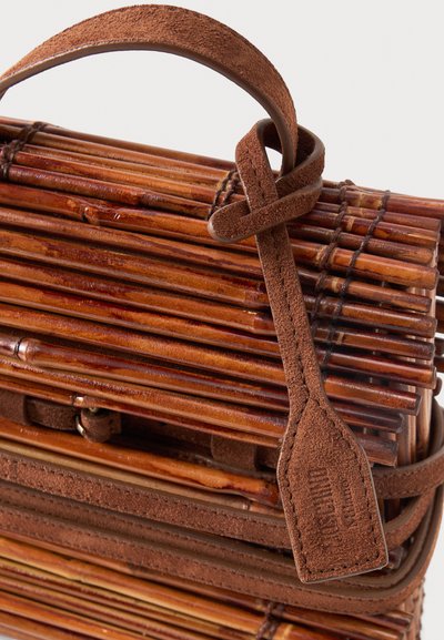 Καφέ τσάντα από μπαμπού με σουέντ χειρολαβή και ραμμένη δερμάτινη ετικέτα με ανάγλυφο όνομα και λογότυπο της μάρκας.