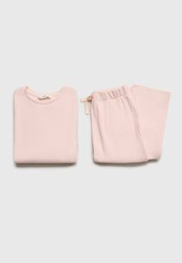 Light pink ribbed loungewear set consisting of a long-sleeve top and matching pants with an elastic waistband and drawstring detail.