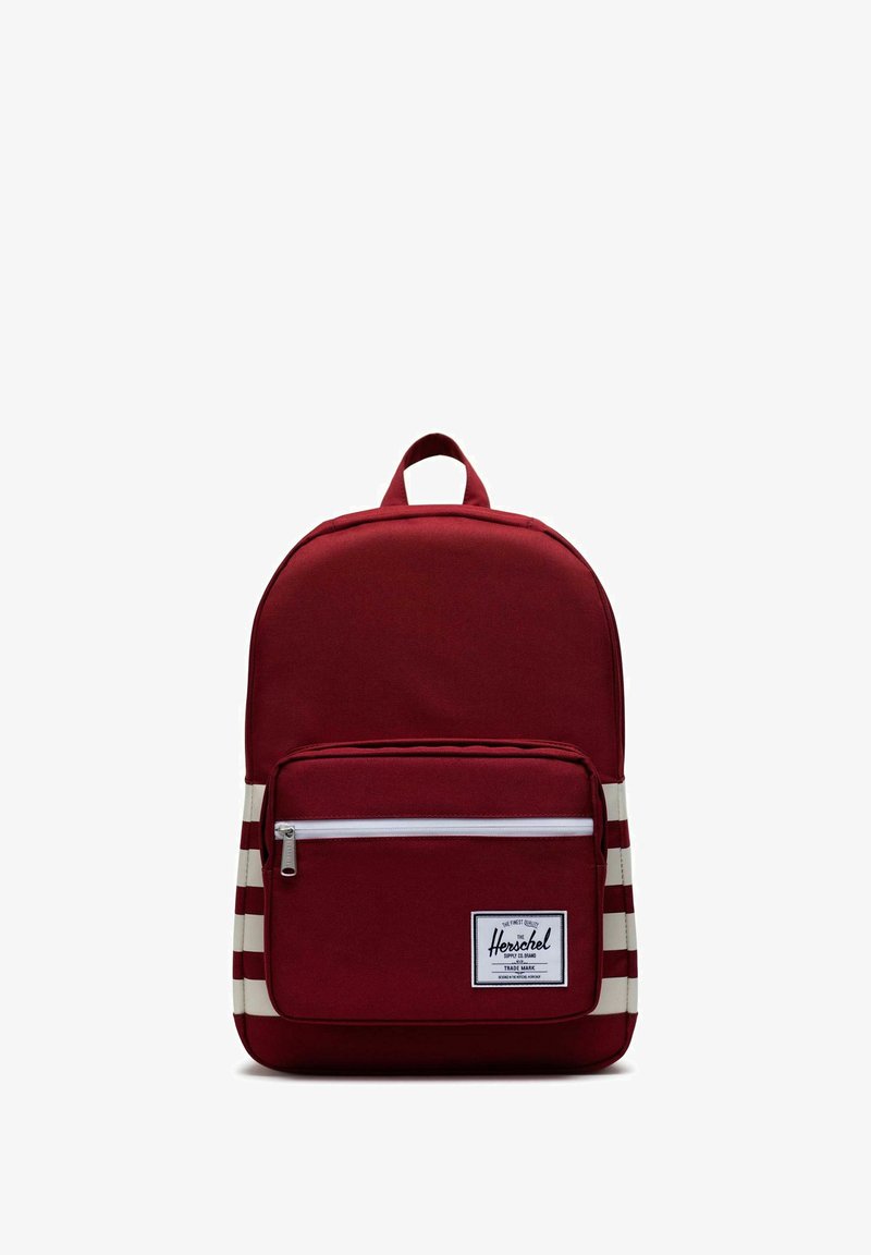 Sac à dos en tissu rouge avec un dessus arrondi, une poche zippée blanche et des accents rayés sur les côtés. Dispose d'une poignée supérieure pour le transport.