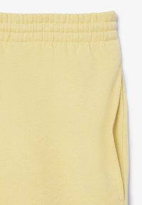 I pantaloni della tuta giallo chiaro presentano una cintura elastica, una texture morbida e tasche laterali con un design semplice.