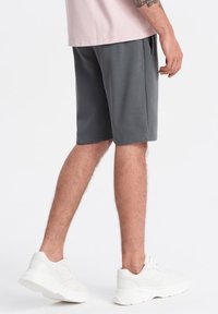 Grå bomuldsblandingsshorts med sidelommer, med en afslappet pasform. Sammen med kraftige hvide sneakers for kontrast.