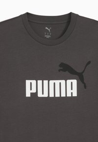 Sötétszürke pamut póló, fehér "PUMA" logóval és egy fekete sziluettel, amely egy ugró pumát ábrázol a mellkas bal oldalán.