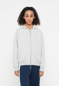 Gray zip-up hoodie made of soft cotton material, featuring a hood, ribbed cuffs, and a simple logo on the left chest.