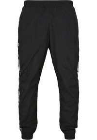 Schwarze, leichte Trainingshosen mit einem elastischen Bund, featuring kontrastierenden Seitenstreifen und schmal zulaufenden Knöcheln. Glatte Textur, sportliches Design.