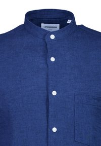 Camicia di lino blu con colletto alla cinese, patta anteriore con bottoni bianchi e una singola tasca sul petto. Design texturizzato e slim fit.
