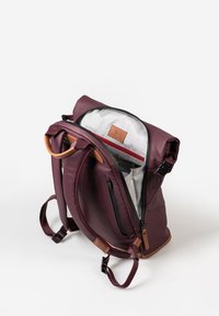 Zaino bordeaux con design a roll-top, caratterizzato da dettagli in pelle. L'interno presenta una fodera a fantasia e numerosi scomparti per l'organizzazione.