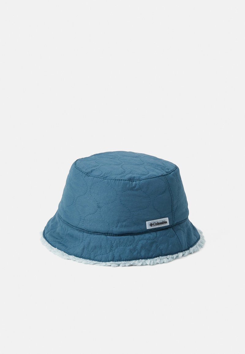 Chapeau bob matelassé bleu avec une doublure en polaire blanche visible au bord et une petite étiquette logo Columbia sur le côté.