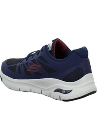 Baskets de sport bleu marine avec tige en maille, semelle blanche et accents rouges. Dotées d'un col rembourré et de la technologie Arch Fit pour un meilleur soutien.