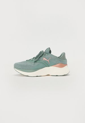 Green knitted Puma sneaker with thick white sole, rose gold Puma logo, and matching green laces on white background.