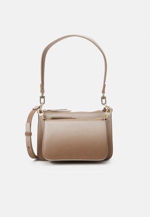 Beige leren handtas met twee vakken met rits, verstelbare schouderriem en korte handgreep met goudkleurige hardware details.