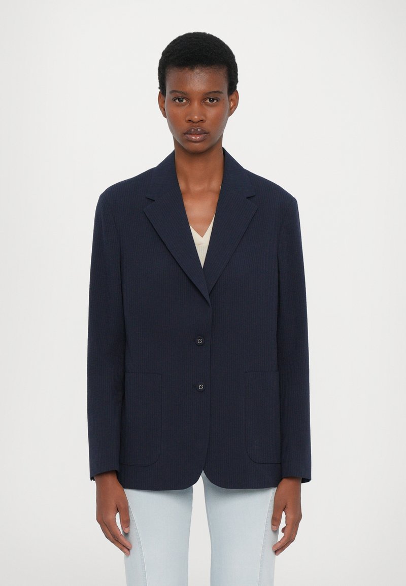 Navy blue blazer with a notched collar, two front pockets, and two buttons. Textured fabric in a structured, tailored design.