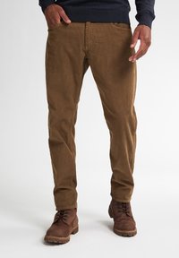Bruine corduroy broeken met verticale ribbels, slim fit, voorzakken en een tailleband; gecombineerd met bruine veterschoenen.