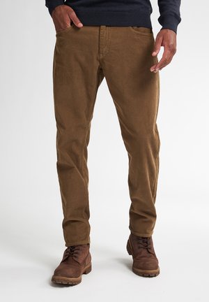 Pantaloni di velluto a coste marroni con righe verticali, slim fit, tasche frontali e cintura; abbinati a stivali marroni con lacci.