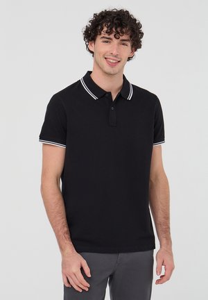 Polo shirt in cotone nero con colletto caratterizzato da strisce bianche, maniche corte e orlo dritto. Nessun motivo o dettaglio visibile.