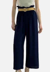 Marineblaue Hosen mit weitem Bein und einem gerafften Bund, ausgestattet mit einem gewebten hellbraunen Gürtel und einer runden Schnalle. Weicher, fließender Stoff mit lockerem Sitz.