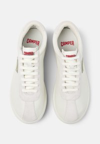 White sneakers made of leather and suede, featuring flat laces, a textured surface, and red "CAMPER" branding on the insoles.