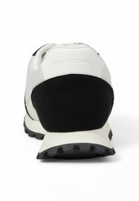 Sneaker noir et blanc avec une tige texturée, des accents en daim, une semelle rembourrée et un design de semelle proéminente pour une meilleure adhérence.