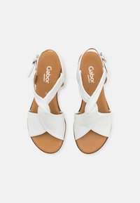 Witte leren sandalen met een kruislings ontwerp van banden, voorzien van een bruine binnenzool en een zijrits voor gemakkelijke in- en uittrekking. Gabor merk weergegeven.