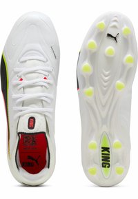 Valkoiset jalkapallokengät, joissa mustia ja neonkeltaisia yksityiskohtia, "KING"-brändäys kielen ja pohjan kohdalla, ja läpikuultava nastallinen pohja näkyvissä ylhäältä ja alhaalta.