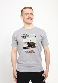 Šedé tričko s krátkým rukávem s grafickým potiskem barevné sochy a textem v různých písmenech a barvách, umístěním na světlém pozadí.