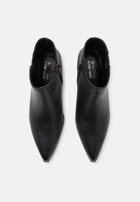 Pair of black pointed-toe ankle boots with side zippers, made from vegan material, viewed from above on a white background.