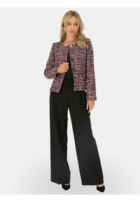 Tweedowa kurtka w kolorze fioletowym, różowym i czarnym z okrągłym dekoltem, zapięciem na zatrzaski z przodu oraz długimi rękawami, w zestawieniu z czarnymi spodniami o szerokich nogawkach.