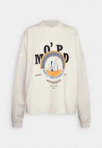 Sudadera crema con cuello y puños acanalados, que presenta texto en negro y azul y un gráfico de edificios abstractos en un diseño circular.