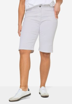 Shorts de Bermuda gris clair en tissu doux, avec une coupe slim, une fermeture à boutons et deux poches latérales. Associés à des baskets blanches.