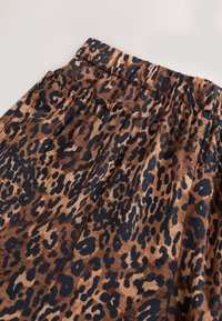 Jupe à motif léopard en marron et marine, dotée d'une ceinture élastique, d'un tissu à texture douce et d'un design plissé.