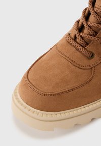 Bottines chelsea en daim marron avec un dessus texturé, une capuchon renforcé et une semelle en caoutchouc beige. Dotées de lacets assortis et d'œillets métalliques.