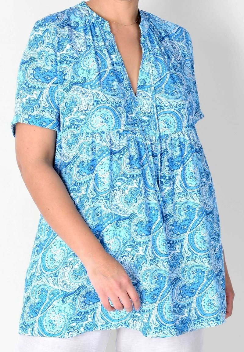Blusa blu con motivo paisley, maniche corte, scollatura arricciata e vestibilità ampia. Realizzata in tessuto leggero, presenta tonalità di blu e bianco.