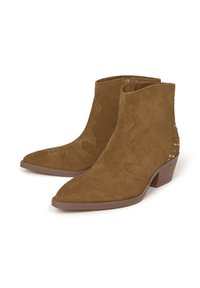 Botas de tobillo de ante marrón con puntera afilada, que presentan costuras decorativas y acentos de tachuelas en los lados. Tacón bajo y apilado.