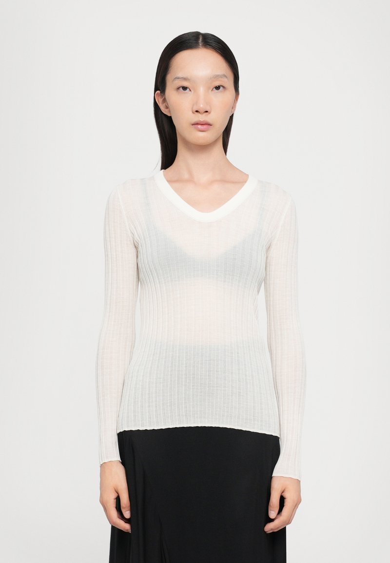 Haut léger à manches longues côtelé dans des nuances de blanc et de gris, avec un col en V et une bordure de cou blanche contrastante. Ourlet sans couture.