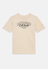 Beige színű pamut póló, kerek nyakkal és rövid ujjakkal. Fekete nyomtatott szöveggel rendelkezik: "JACK&JONES Coll. Studio Since 1990." Egyszerű dizájn.