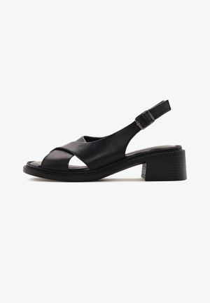 Black leather women's slingback sandal with a low block heel and crisscross straps over the toes, secured by an adjustable buckle.