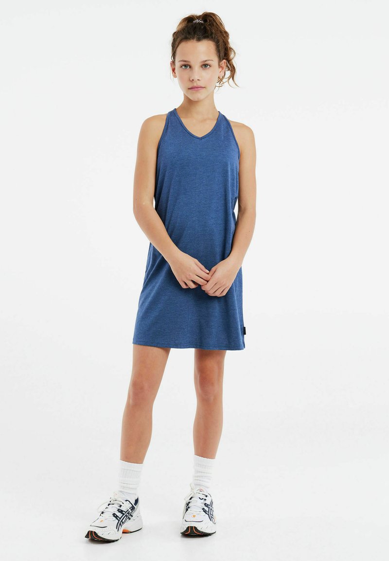 Bezrukavna plava atletska haljina s V-izrezom, izrađena od mećeg materijala. Model nosi bele i tamnoplave atletske cipele s vidljivim čarapama.