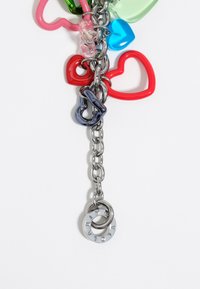Ketting met meerkleurige plastic hartvormige bedels (rood, groen, roze, blauw) en een zilver hardware detail met gegraveerde ringen en rhinestones.