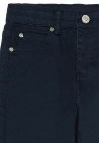 Tumedat meresinine denim püksid, millel on hõbedane riistvara, viis taskut ja klassikaline lõige minimaalse õmblusdetailiga.