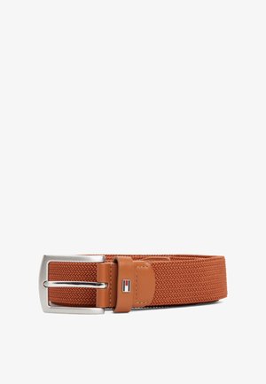 Brązowy pasek z tkaniny o splocie, ze srebrną klamrą i jasnobrązowymi skórzanymi akcentami, z małym prostokątnym emblematem w kolorach czerwonym, białym i niebieskim.
