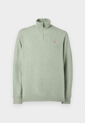 Svijetlozeleni pulover s polu-zip ovratnikom, dugim rukavima i izvezenim logotipom na prsima. Napravljen je od mekog, strukturiranog materijala.