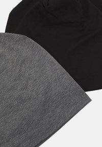 Dos gorros de lana, uno negro y otro gris jaspeado, hechos de un tejido suave y elástico. El gorro gris tiene una textura sutil, mientras que ambos son sin costuras.