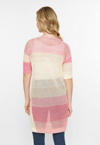 Tunic lunga a maglia aperta in sfumature graduali di rosa e crema, con maniche corte e un design ampio e arioso.