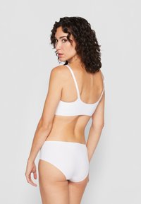 Hvit undertøysett med sømløs bralette og høytaljede truser. Glatt stoff med justerbare stropper og minimalistisk design.