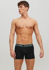 Fekete pamut boxer alsónadrág zöld és fehér derékszíjjal, amelyen a "JACK & JONES" felirat található, testhezálló fazon és sima textúra jellemzi.