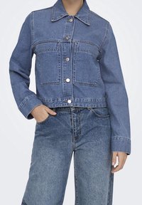 Jeansjacka i mellanmörk blå, har en knappframsida, två bröstfickor och en klassisk krage. Avslappnad passform med långa ärmar.