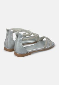 Sandali argento con suola piatta, cinturini con perline e chiusura con zip sul retro. Materiale simile alla pelle morbido con finitura opaca.