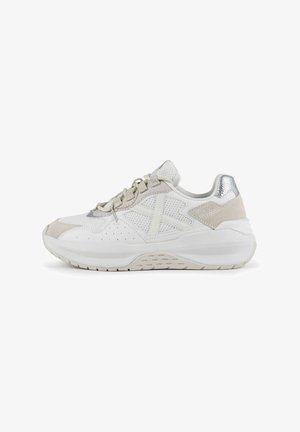 Zapatilla blanca con paneles de malla y ante, acentos metálicos, punta redondeada y suela acolchada con detalles texturizados.