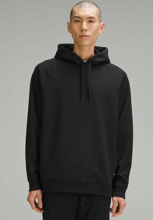 Sweatshirt à capuche noir avec une coupe décontractée, des manches raglan et des cordons de serrage ajustables. Texture lisse et bords en tricot.