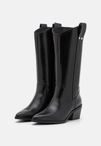 Stivali da cowboy in pelle nera con punta affusolata, tacco medio e cuciture decorative sui lati. Presentano linguette per facilitare l'indossamento.